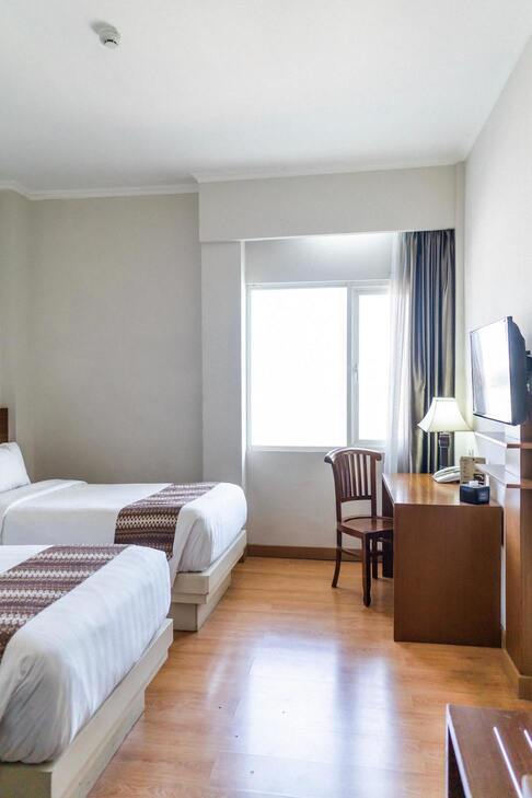 Une chambre avec un lit simple, un bureau et une fenêtre avec des rideaux