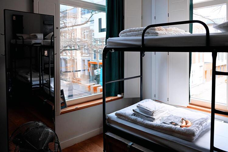 Une chambre avec un lit superposé, une fenêtre ou l'on peut voir la ville et un miroir.