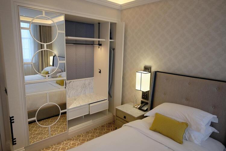 Une chambre avec un lit double, une lampe sur une table de chevet et une armoir à coté du lit.